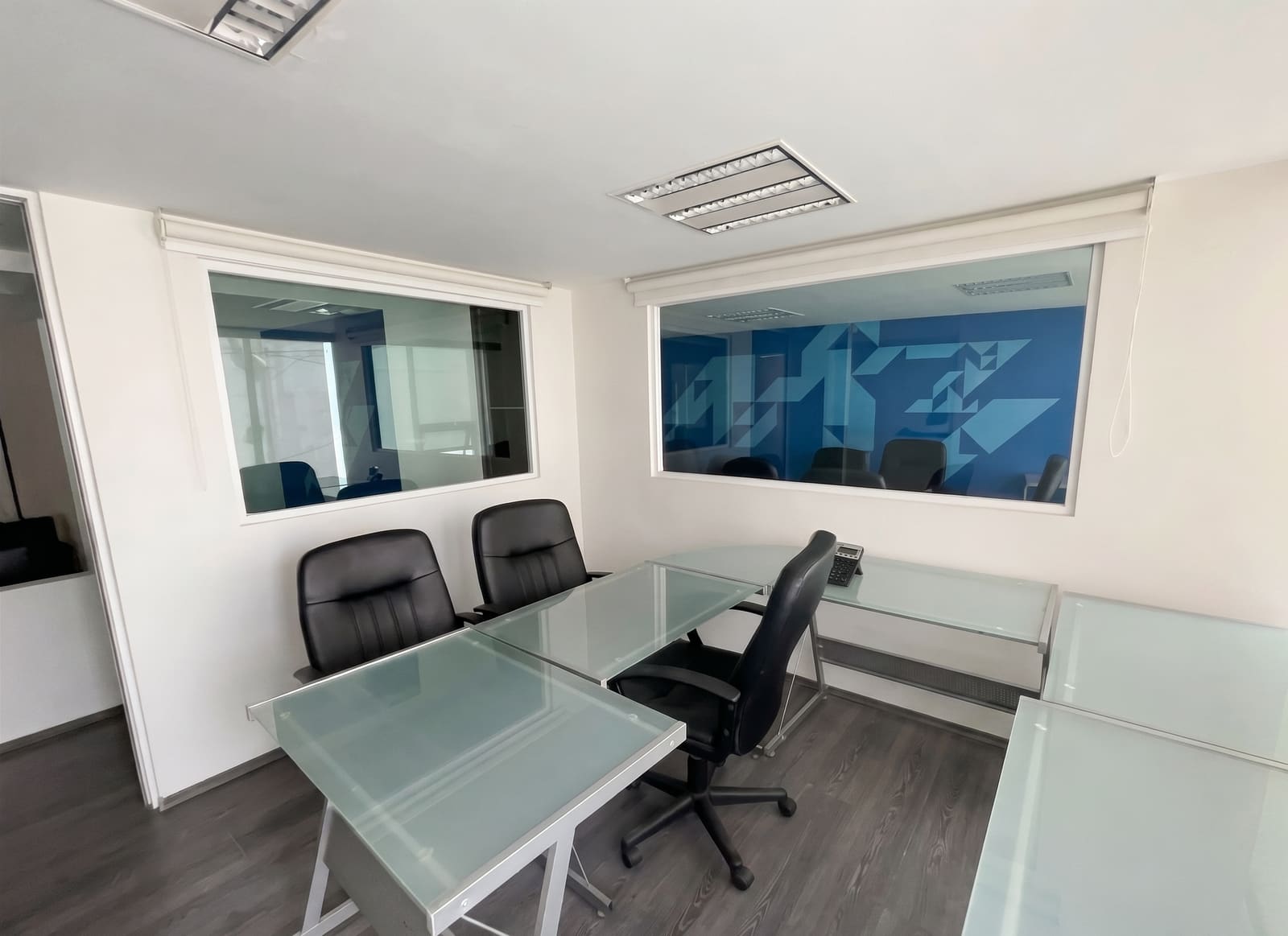 Sala de juntas con mesa de vidrio y sillas ejecutivas