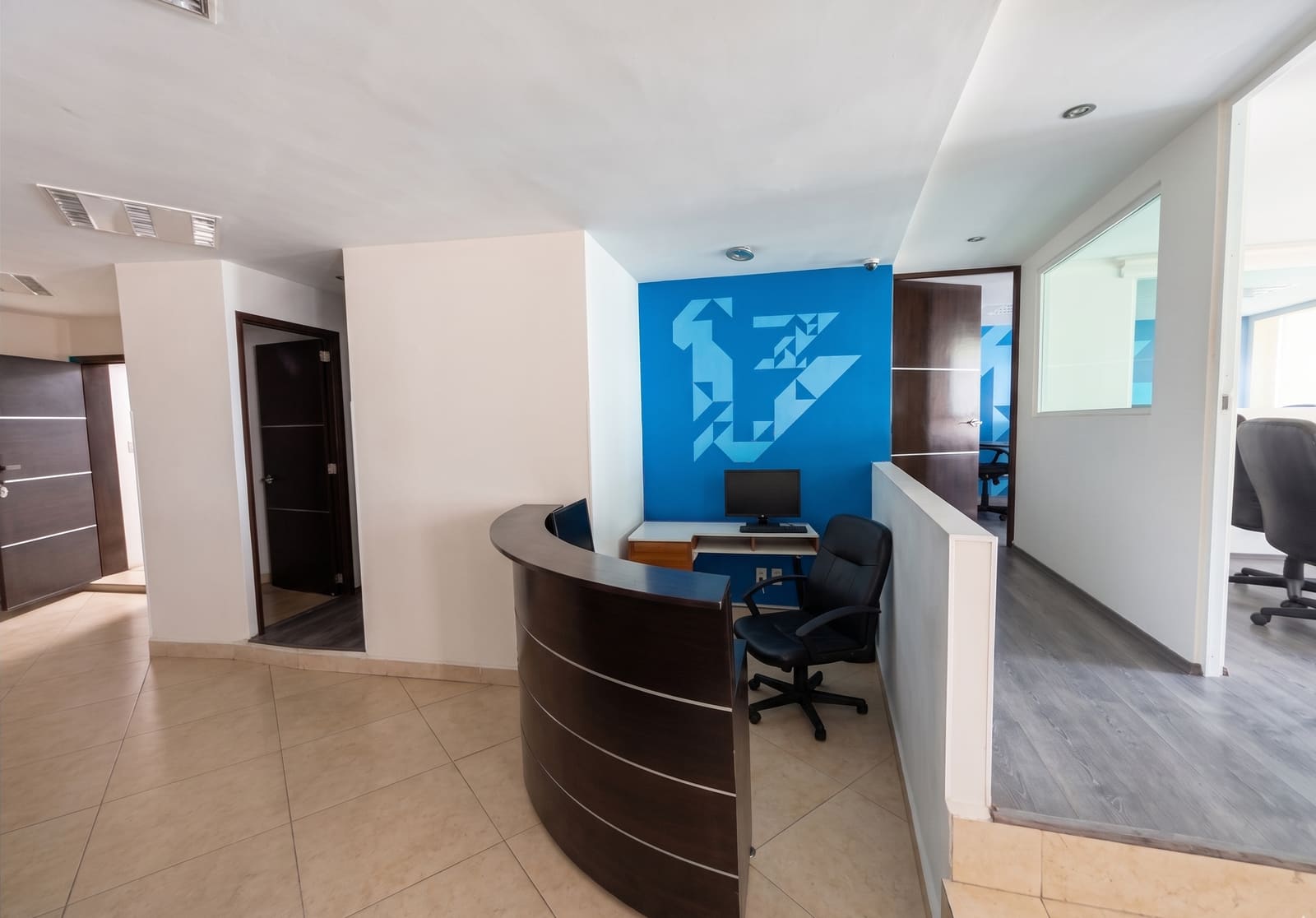 Recepción con muro de acento azul y mostrador de madera oscura