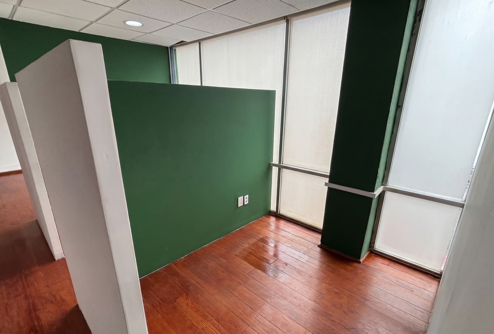 Detalle de divisiones de tablaroca con pared verde y piso de duela de madera