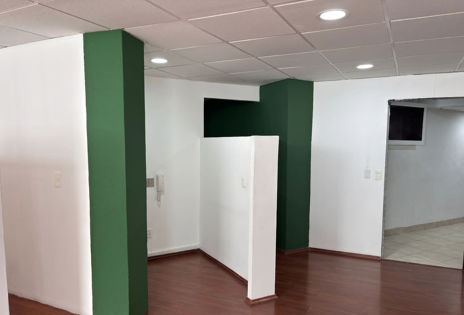 Interior del espacio con columnas y acentos verdes y divisiones blancas removibles