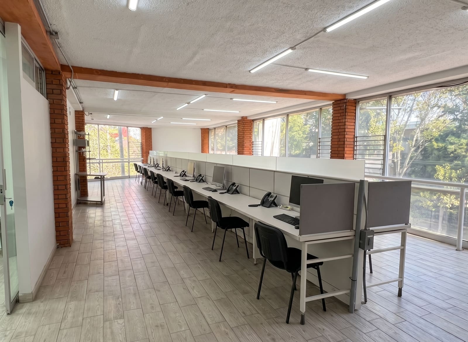 Hilera larga de estaciones de trabajo tipo planta abierta con vista al exterior